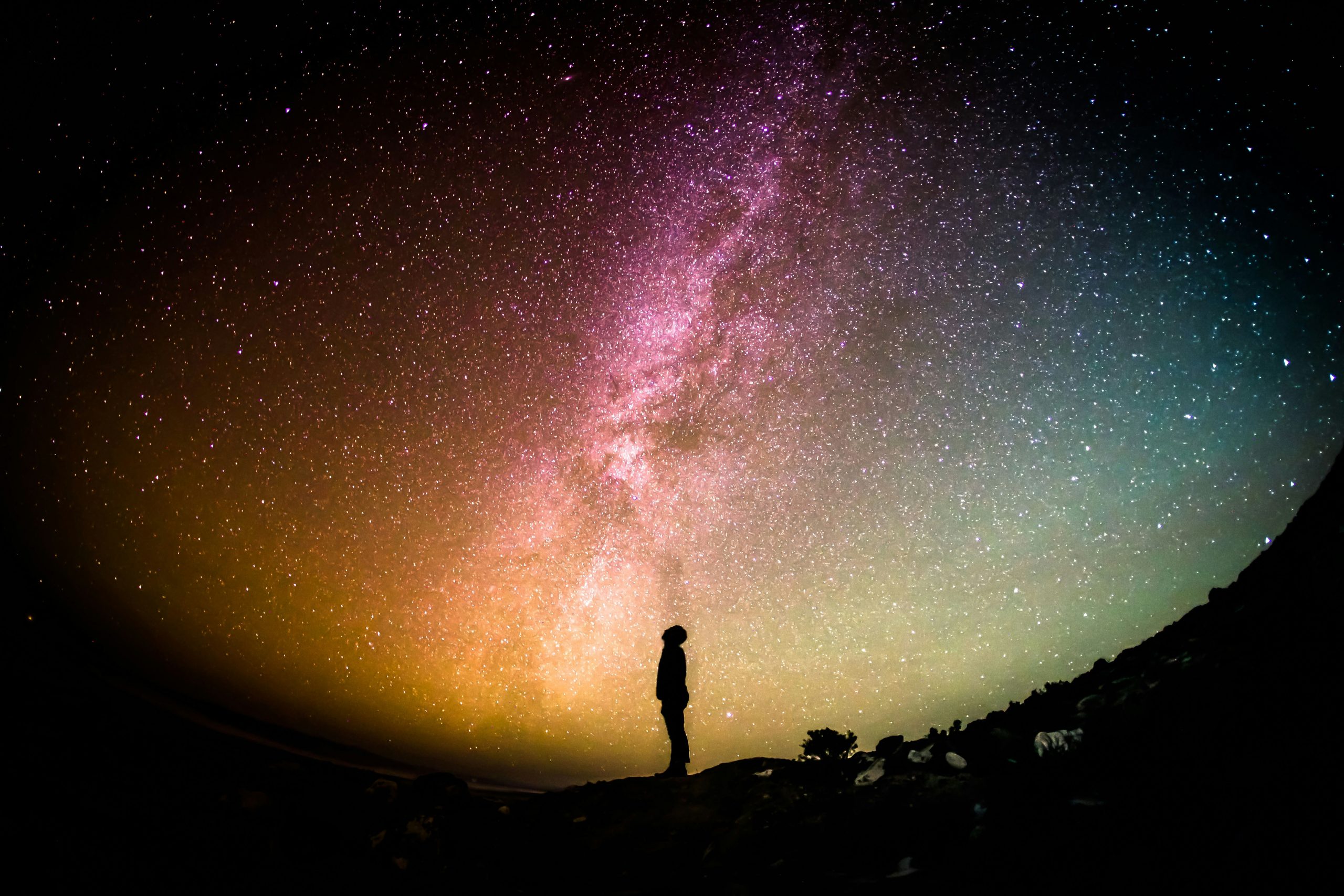 Silhouette of man against colourful starry sky